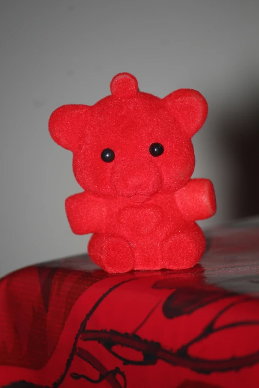 a stuffed animal in red sitting on a red pillow