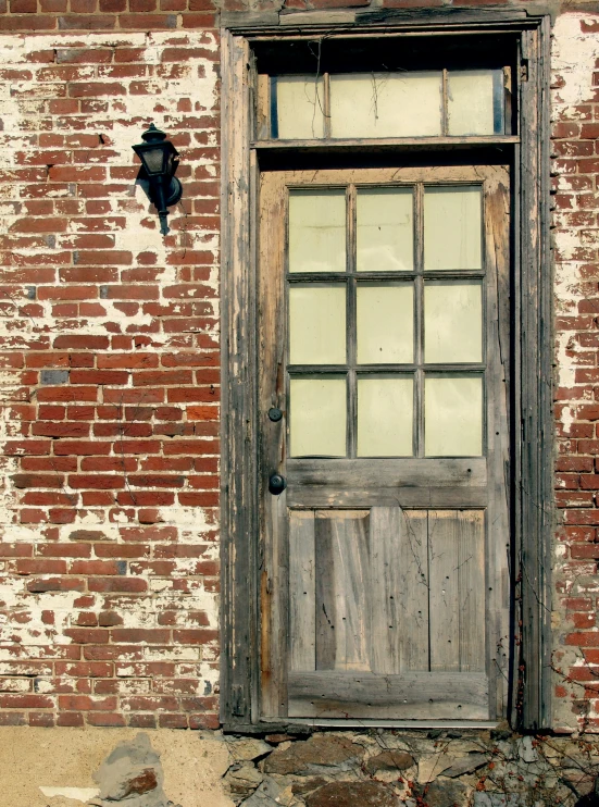 old and dirty door with a missing window on an old brick building