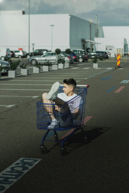 a young man sitting in a shopping cart outside