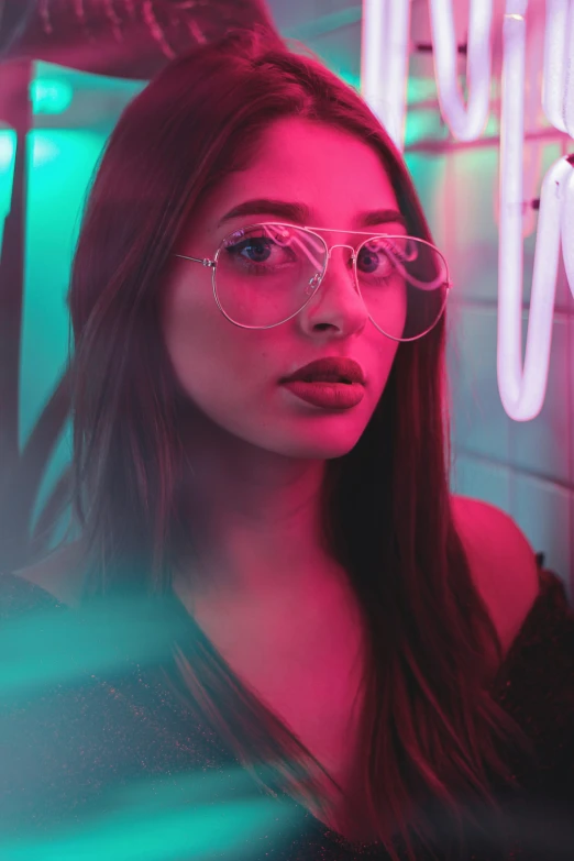 a woman with glasses is standing in front of neon lights