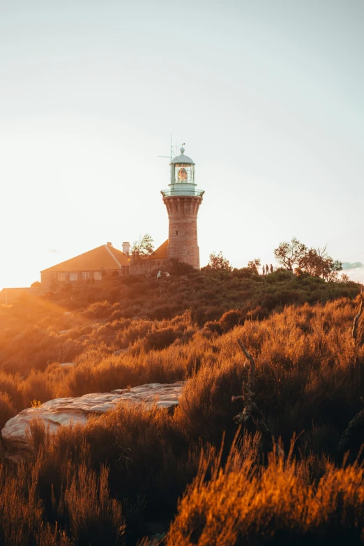 the light house sits on top of a hill in a golden field