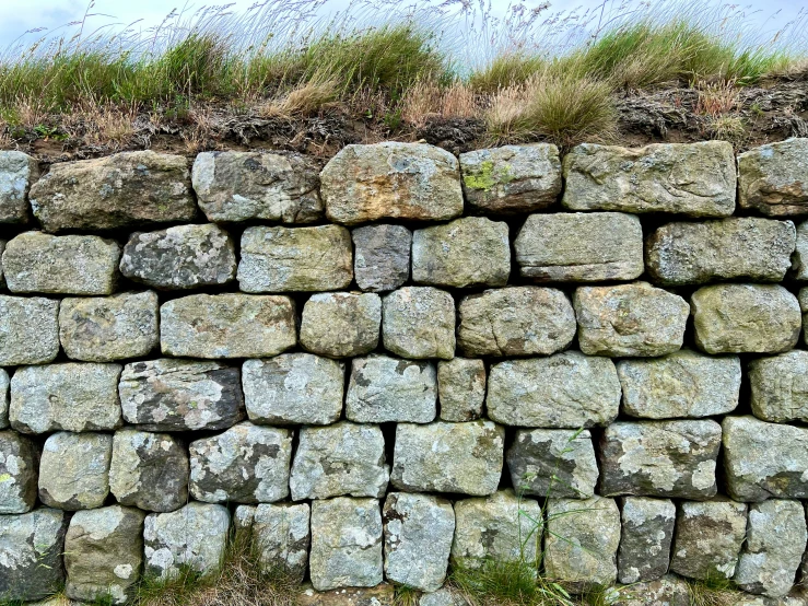 a wall made from many large rocks in a field