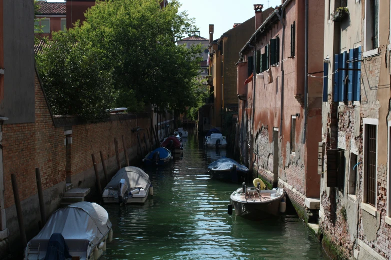 some boats are sitting along a very narrow canal