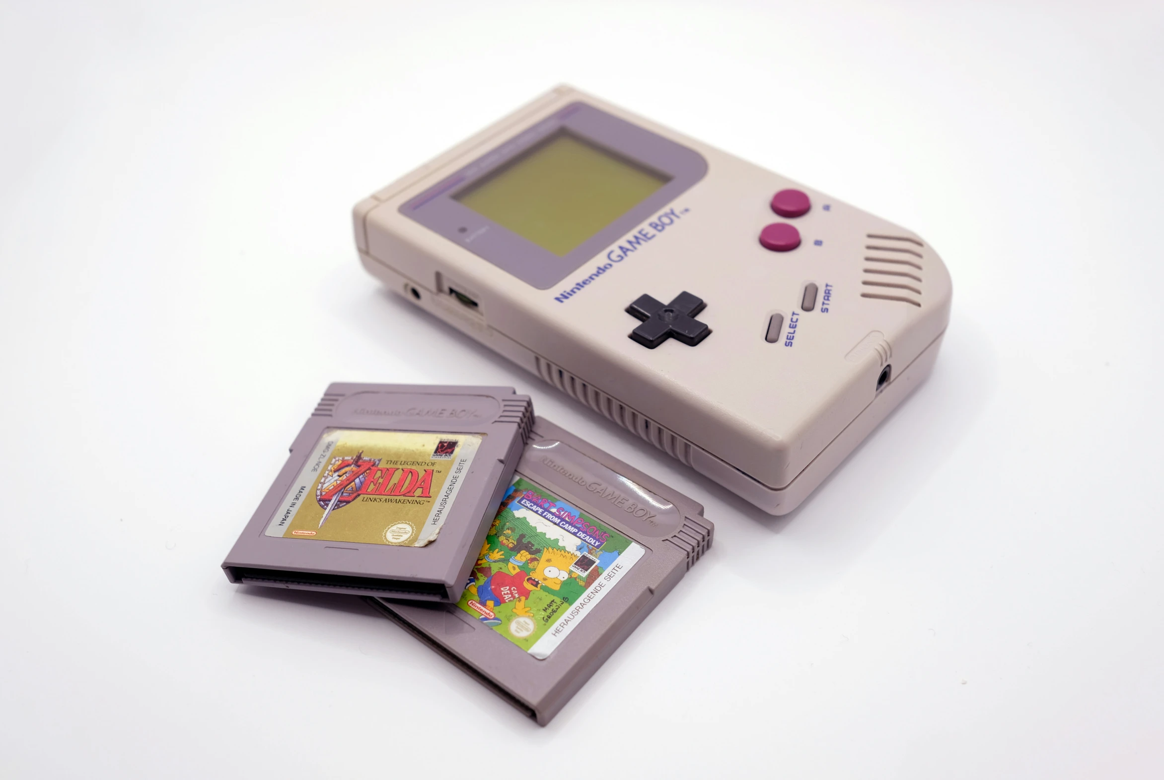 an old fashioned nintendo game boy next to an old nintendo gameboy game