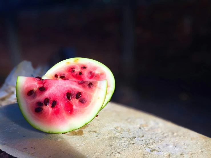 a cut in half slice of watermelon sitting on a rock