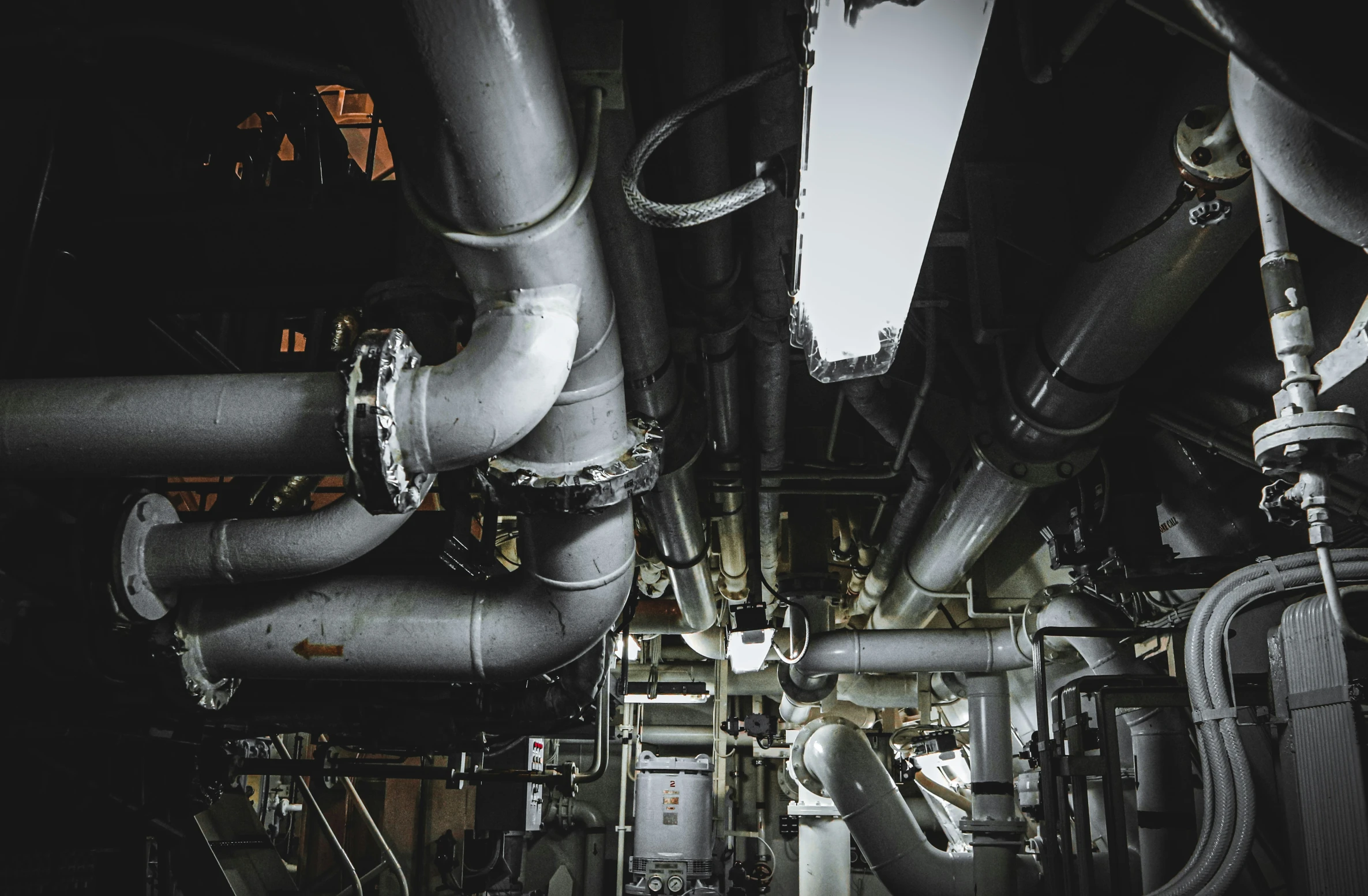 many pipes are running into a room with black walls