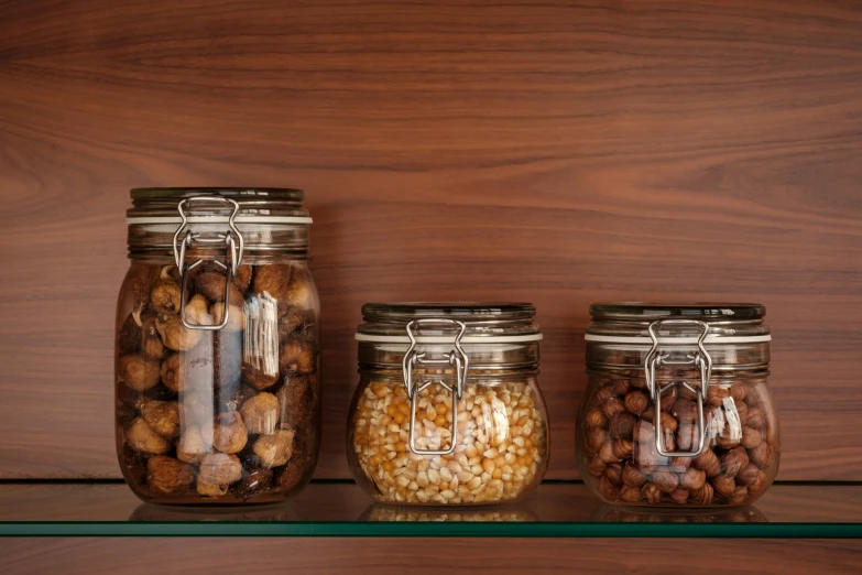 three jars with different types of beans sit on a shelf