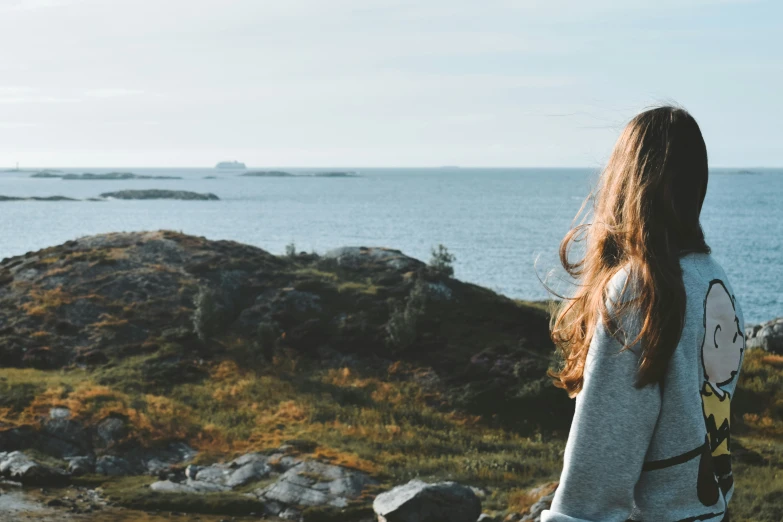 woman overlooking a body of water near rocky cliff