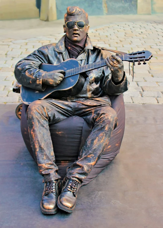 a man sitting down while holding a guitar