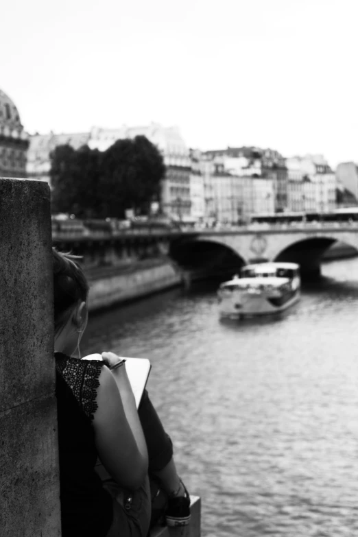 a woman standing on the side of a bridge overlooking a river