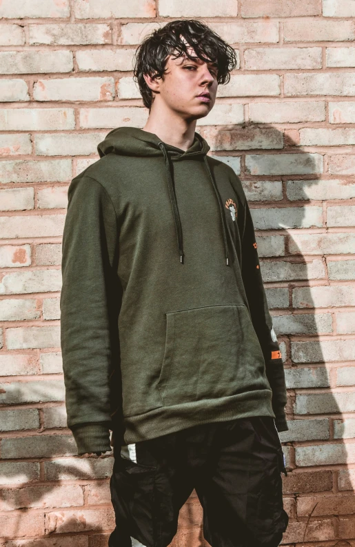 a young man standing in front of a brick wall