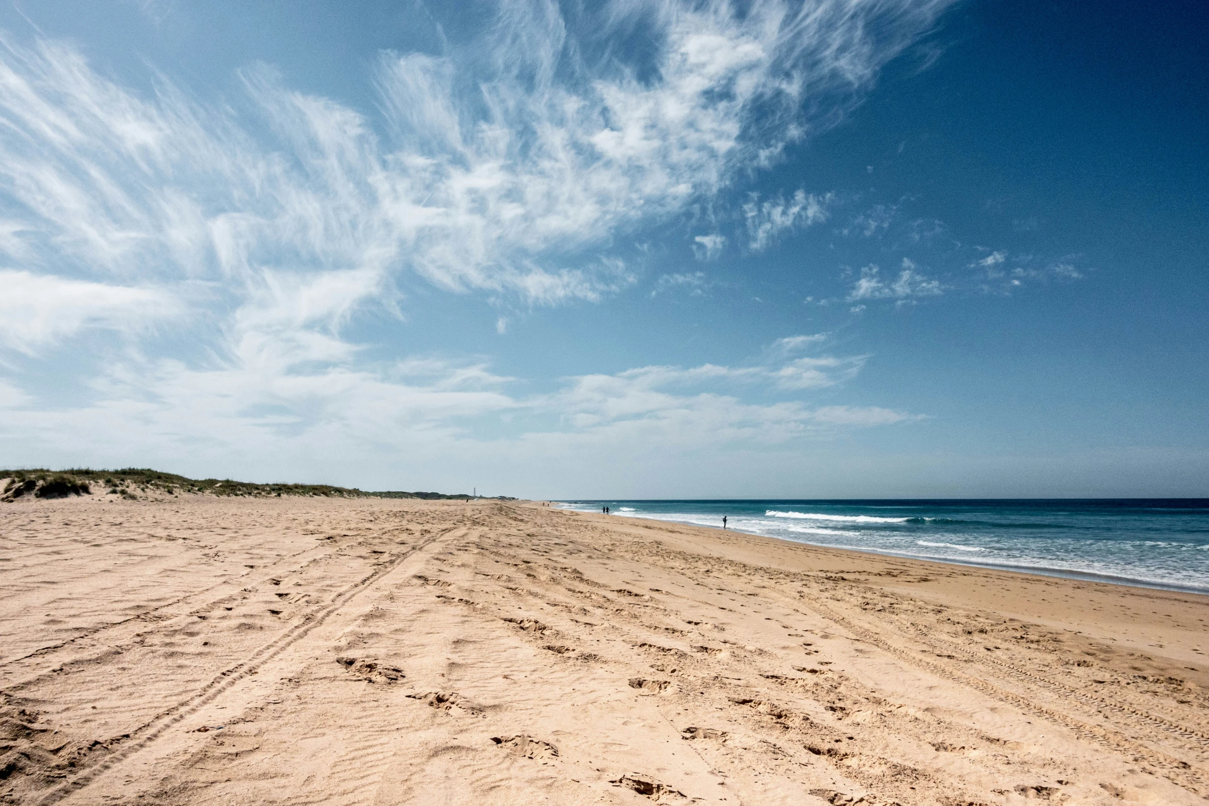 a beach with two people walking across the sand