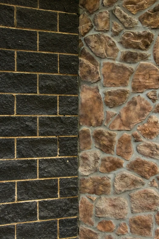 a black cat sits on a bench against a black and stone wall