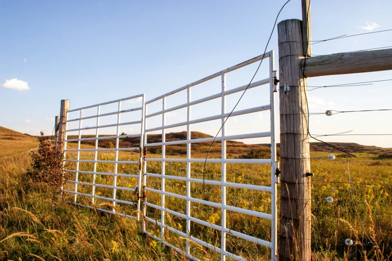 a fence in the grass is next to a hill