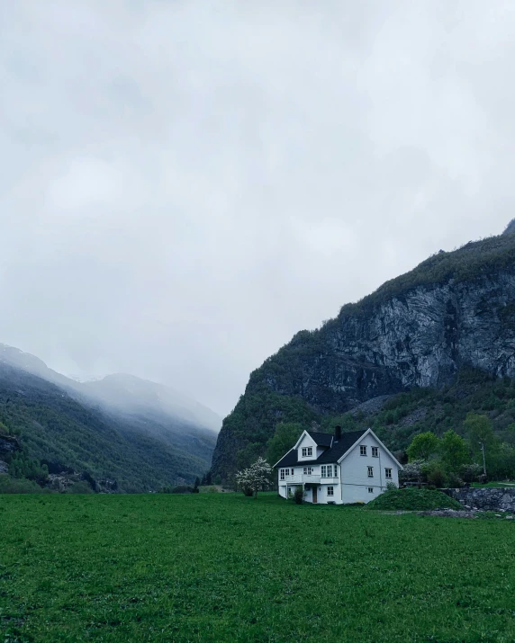 a house sitting in the middle of a green valley