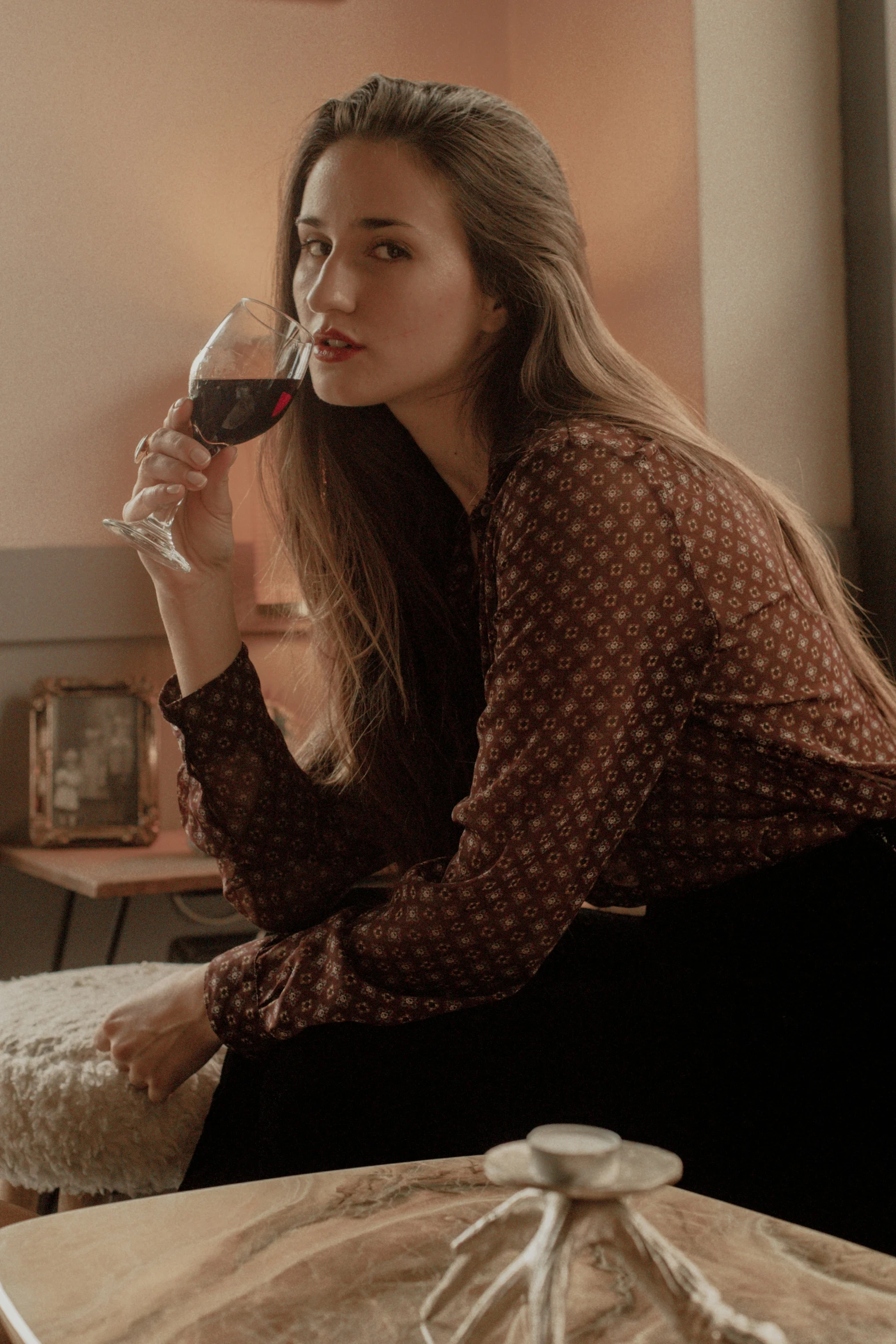 a woman sitting at a table while drinking a glass of wine