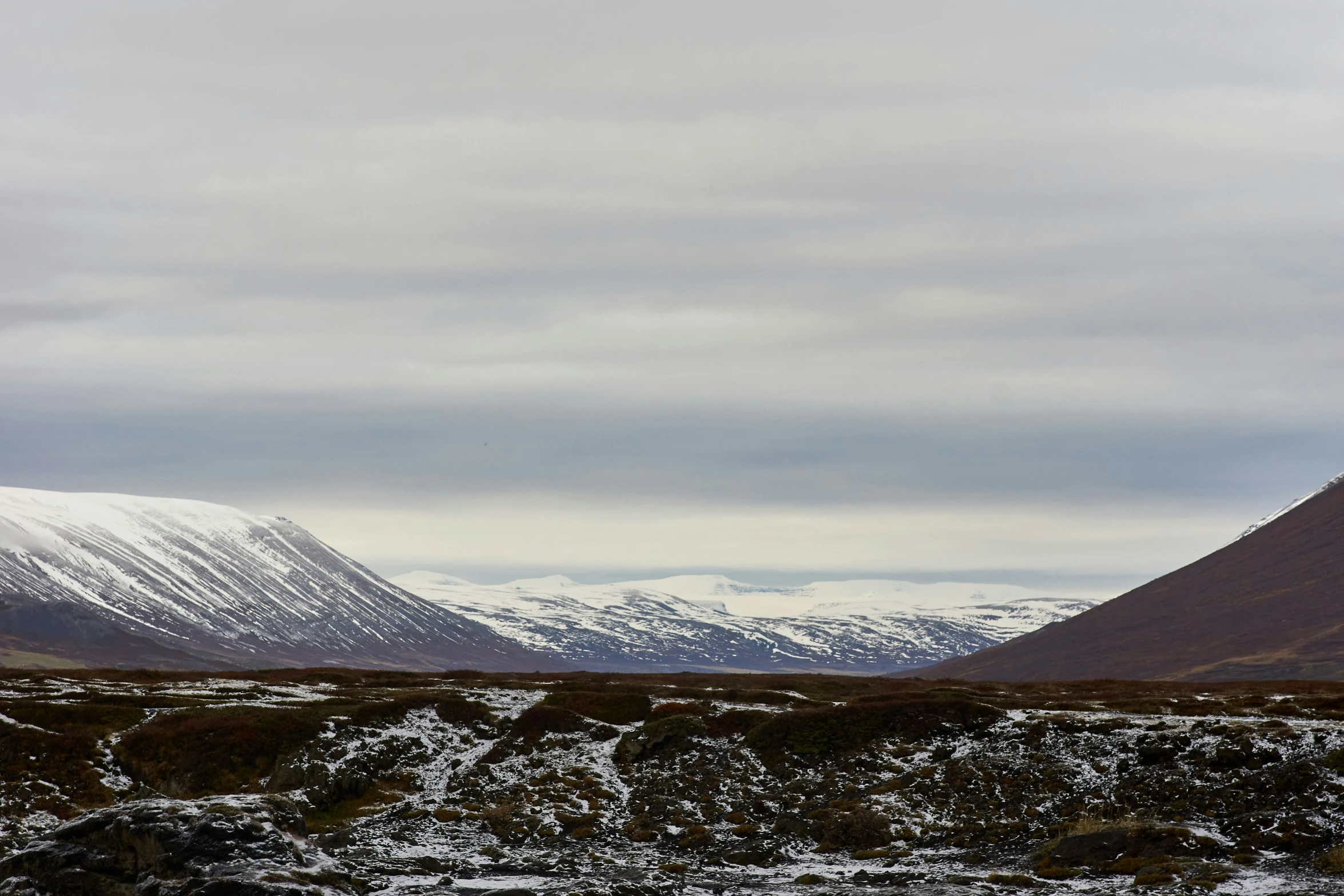 a mountain with some snowy mountains behind it