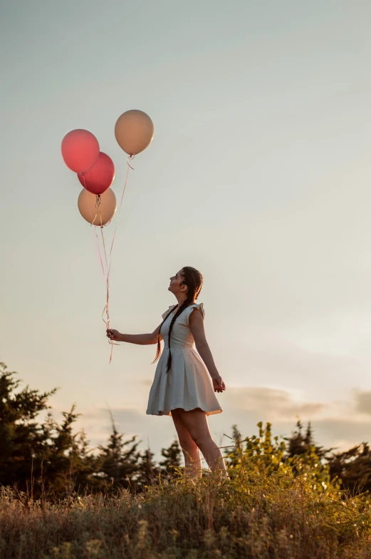 a girl in white dress and red balloons near trees