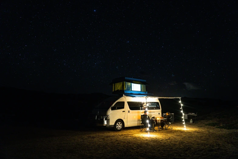 an rv with some people sitting under the lights