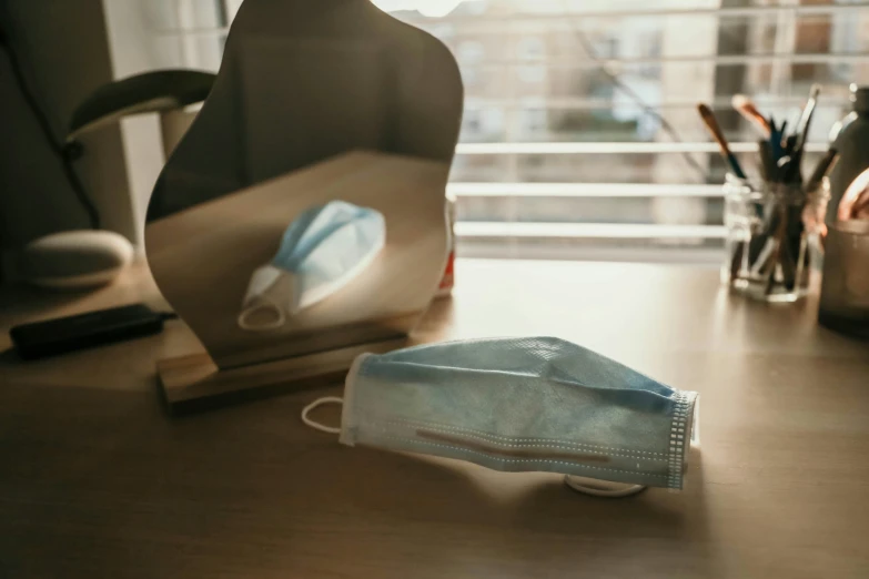 some office supplies sit on a desk by a window