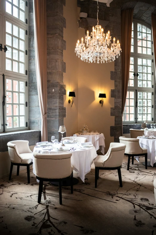 a dining room set for two with chandeliers on the walls and a table