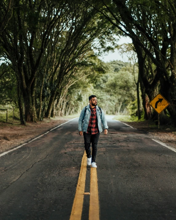 man walking down middle of empty street in the jungle