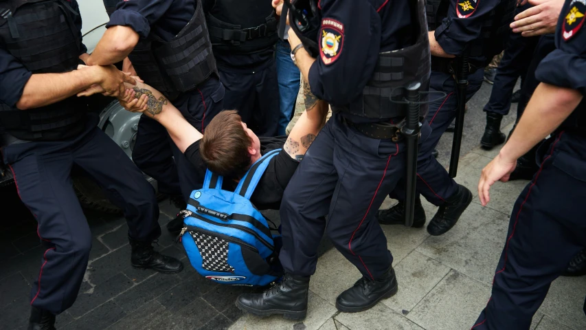 policemen are assisting an unknown man in his backpack