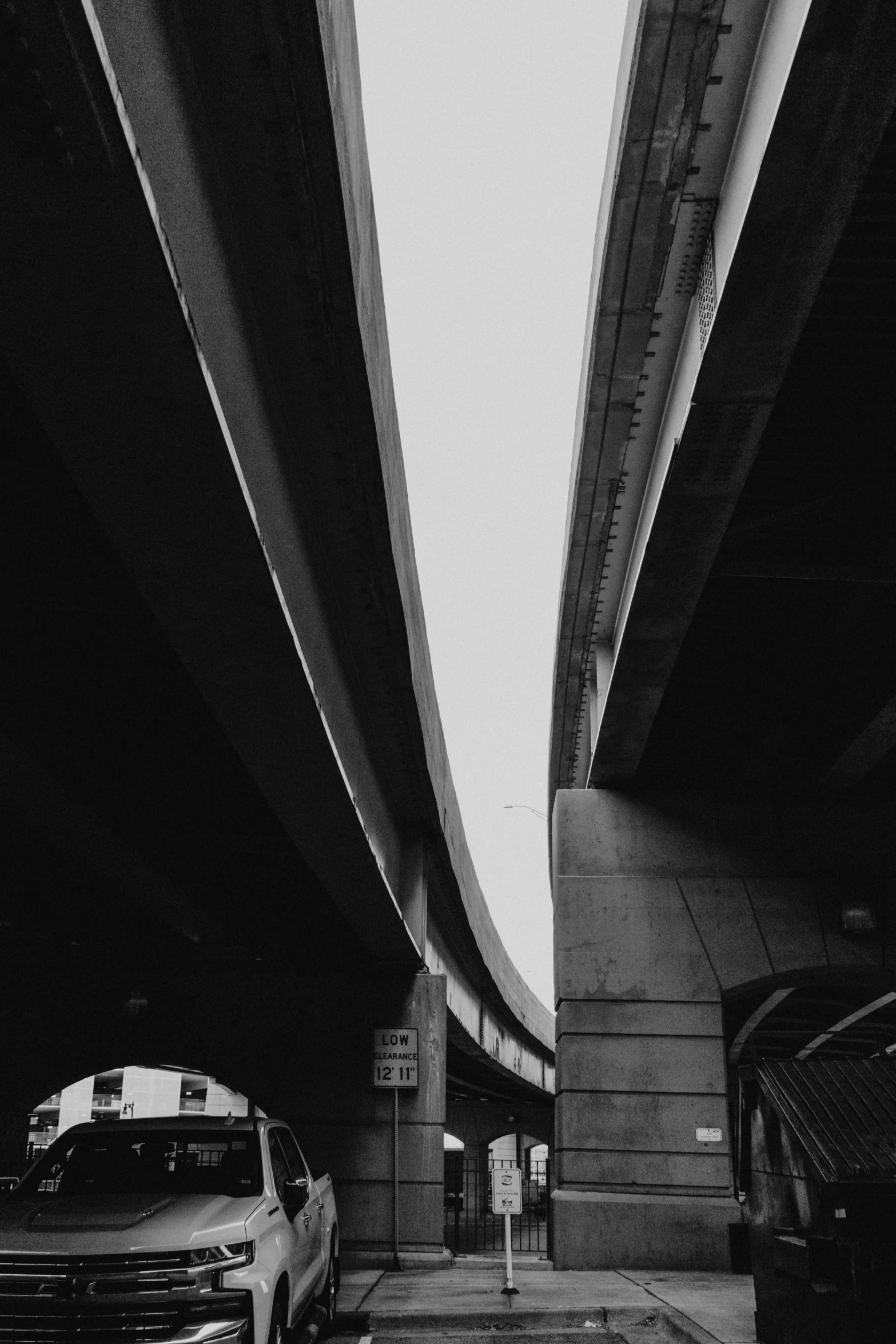 two cars driving underneath a overpass in black and white