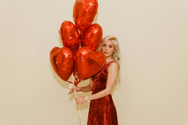 a beautiful woman holding bunch of red balloons