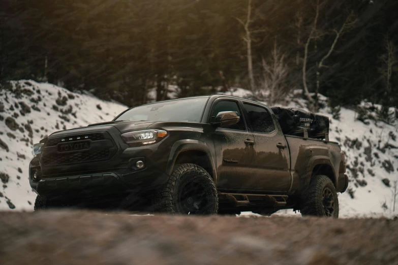 the truck is driving along the snow - covered mountain