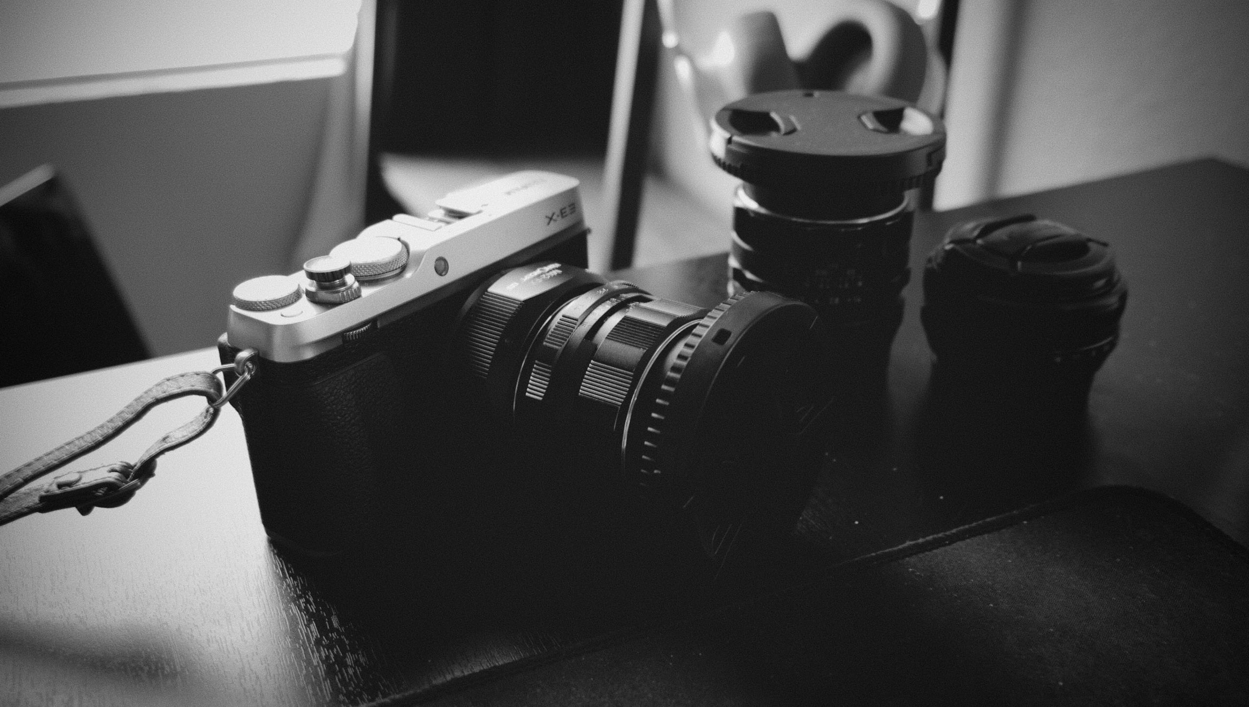 a digital camera is on the table with a long strap attached