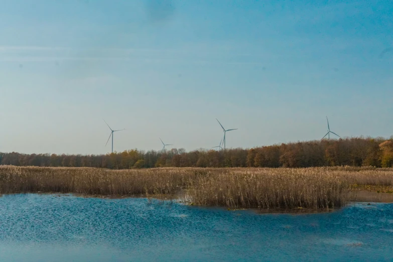 a number of windmills in the sky over water