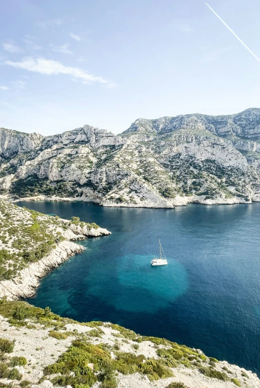 a white boat sits on the water near a hillside