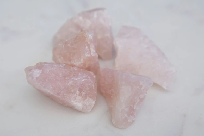 several pieces of pink rock sit on a white marble surface