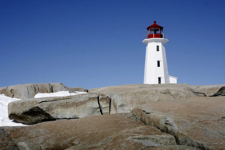 a white and red light house stands atop a rocky hillside