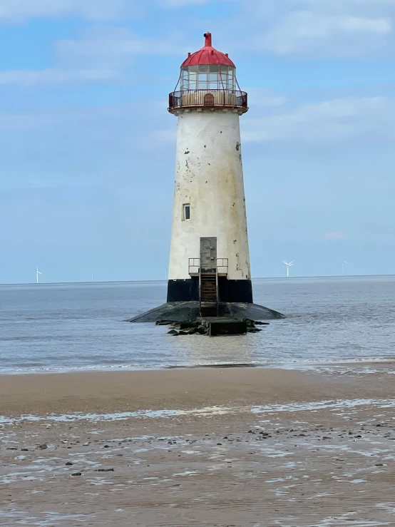 a large light house on the ocean with its red top