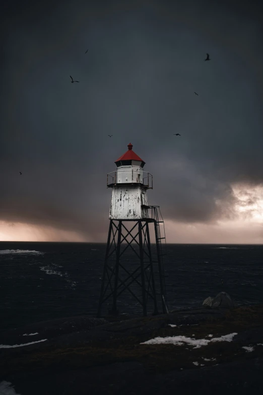 a lighthouse in the middle of the ocean, during dusk