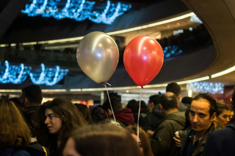 a crowd with balloons are standing outside on a sidewalk