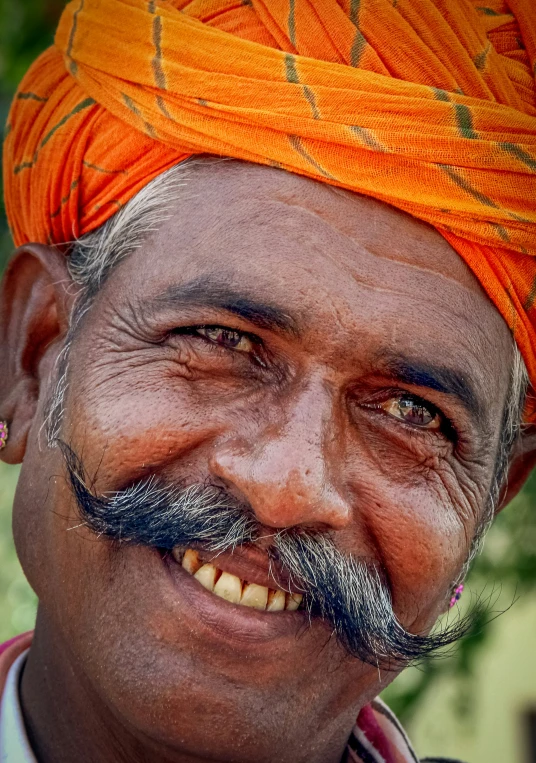 a man in a turban smiling and wearing a red tie