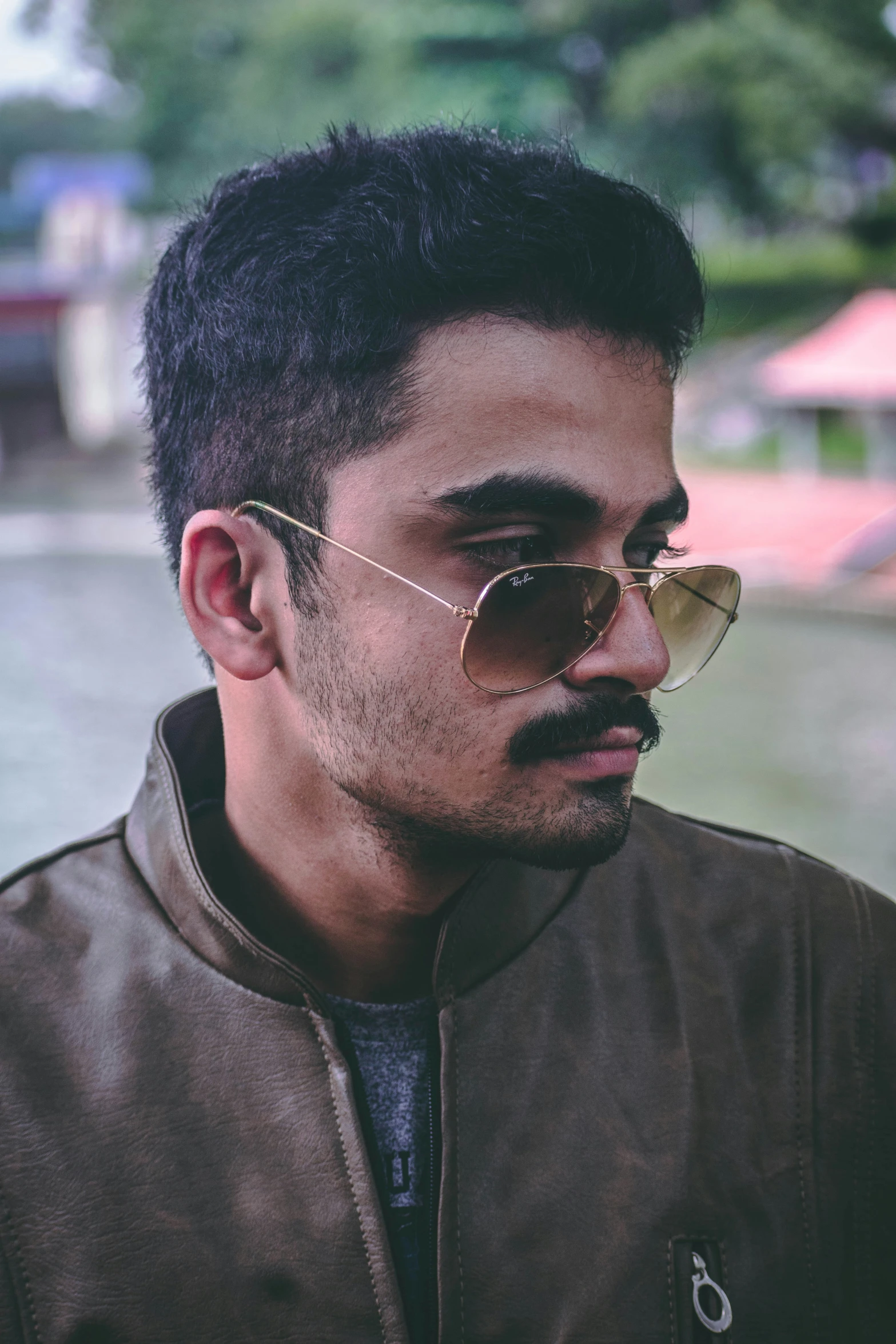 a man wearing sunglasses standing next to a body of water