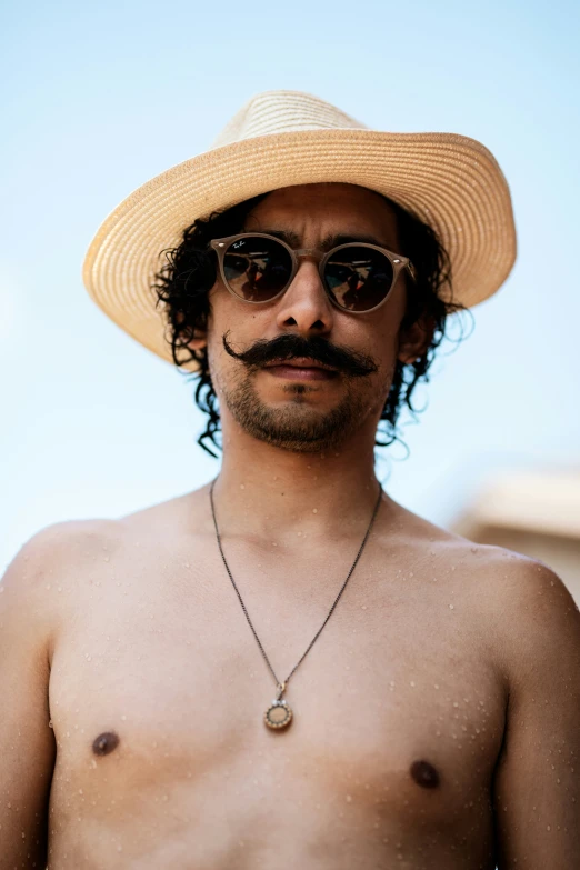 a man with long, curly hair wears a large mustache and big sunglasses