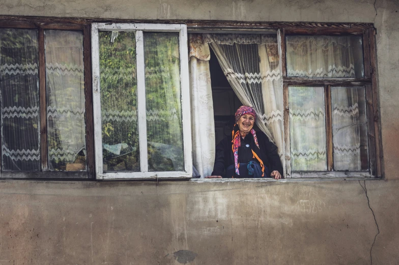 a woman that is looking out a window with her scarf on