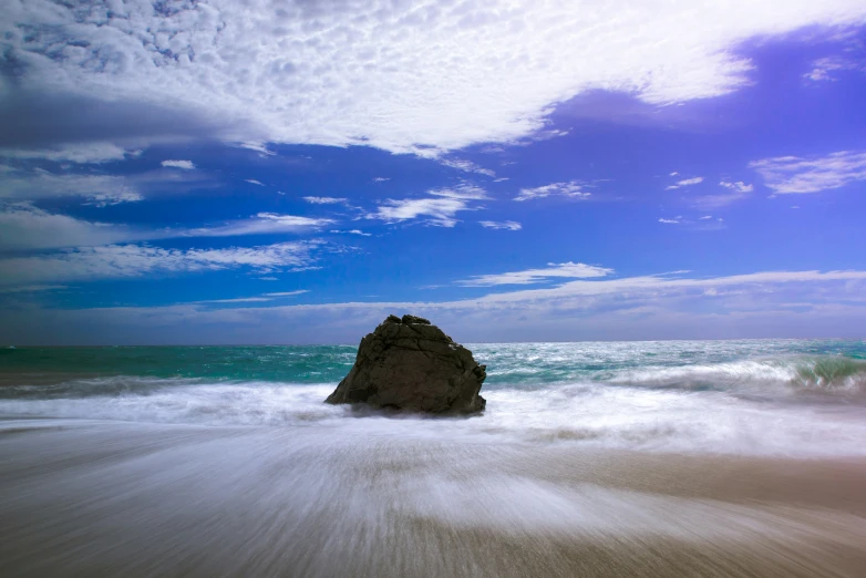 a rock formation stands in the ocean waves