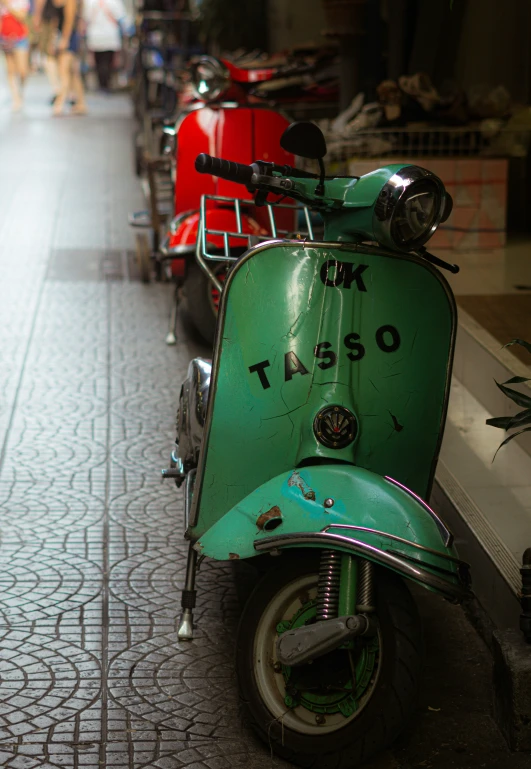 several mopeds parked on a city sidewalk next to each other