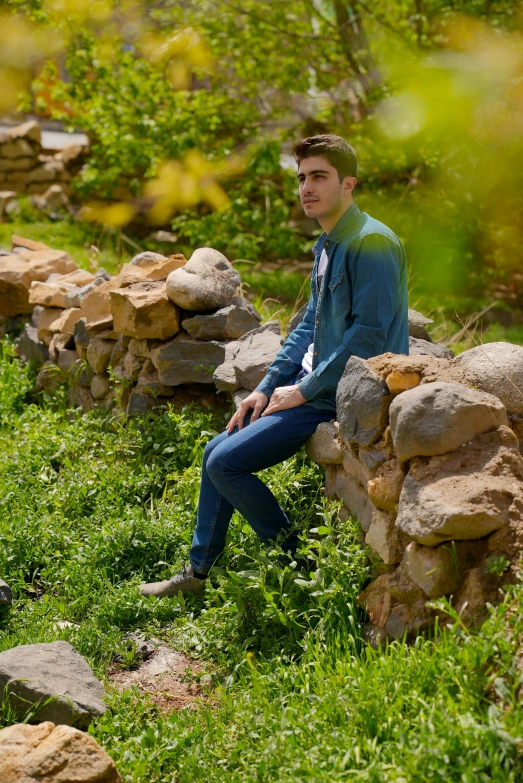 a man sitting on top of a pile of rocks next to a forest