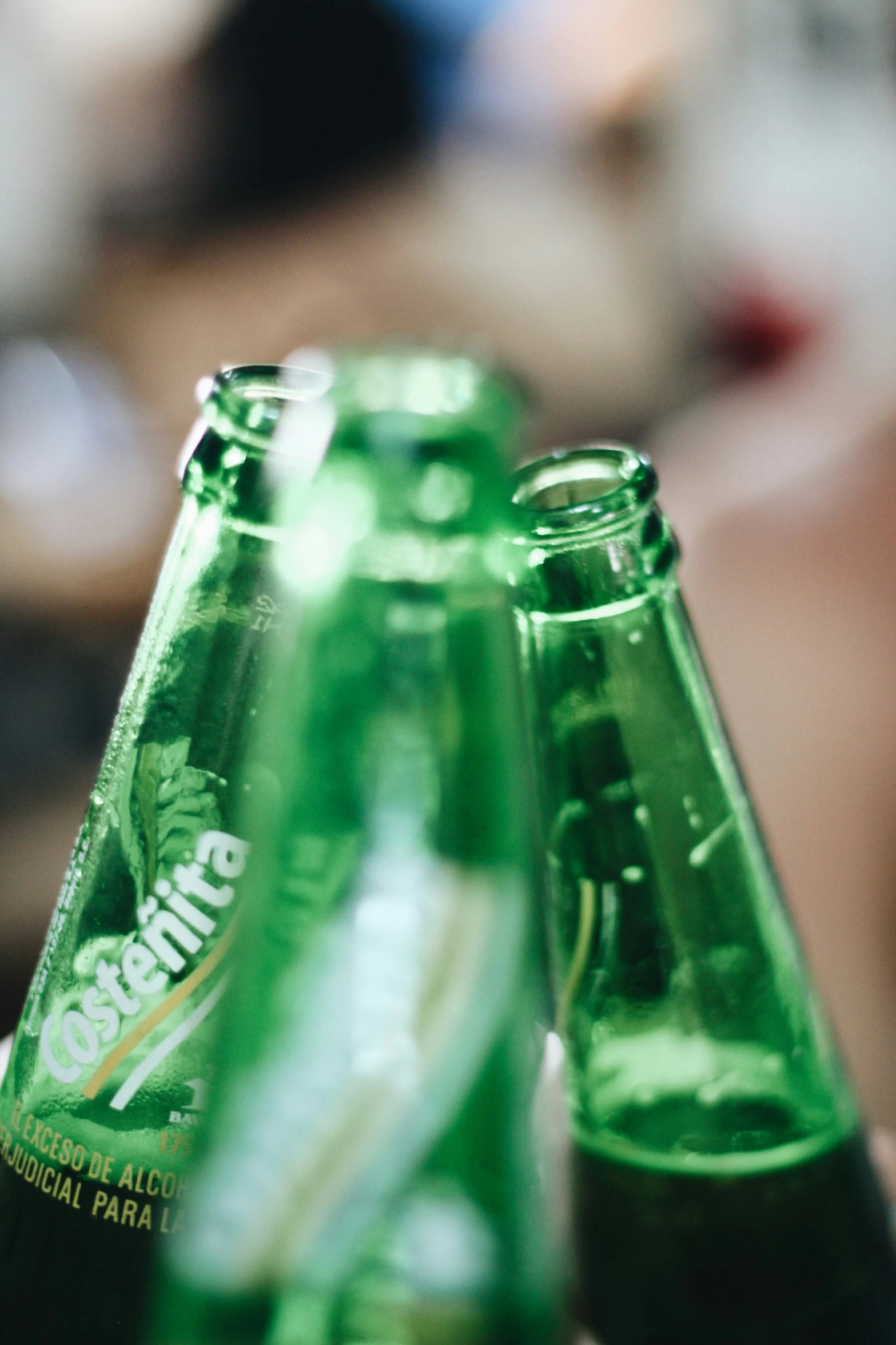 a hand holding three green beer bottles with the label seltings
