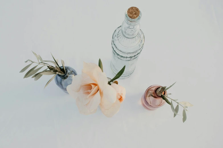 two flowers are in front of a small bottle with cork top
