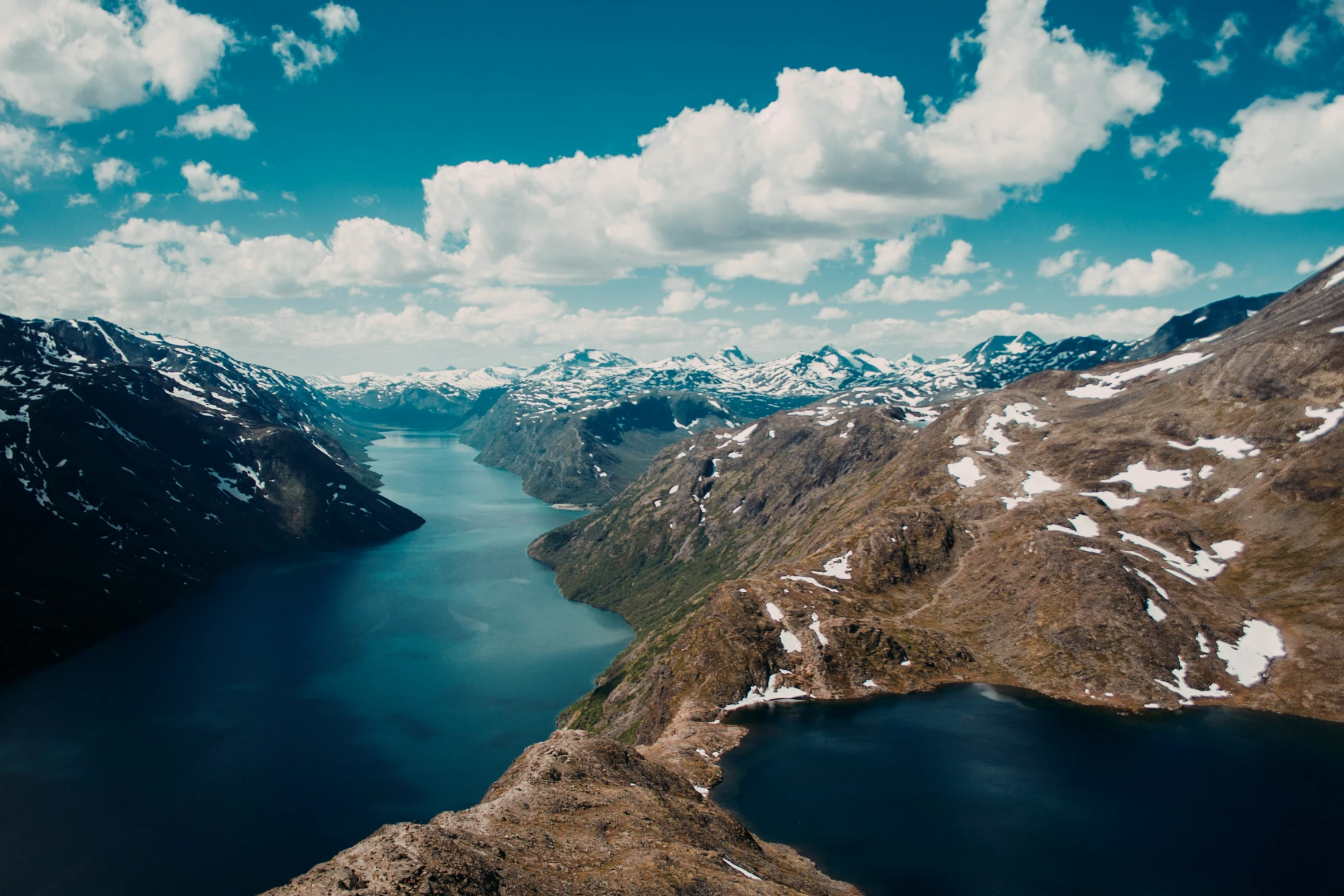 a view of a lake surrounded by mountains and snow