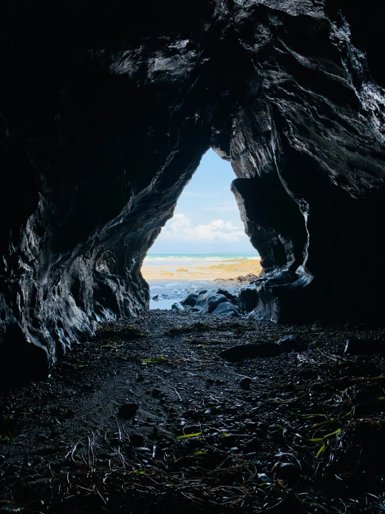 dark beach scene with cave entrance showing blue sky