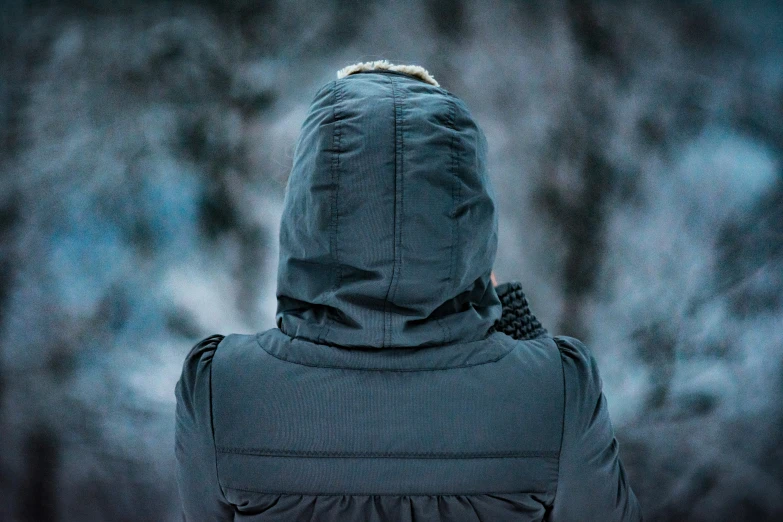 a child wearing a hooded jacket looks out from behind